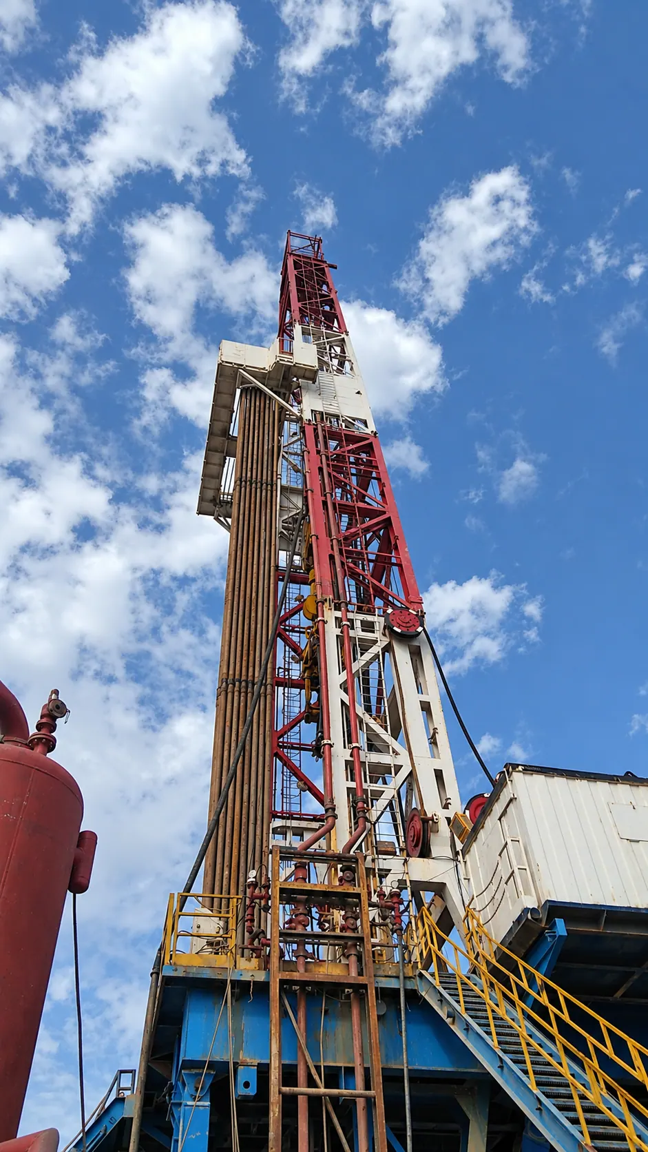 Drilling derrick with racked pipe on a rig site