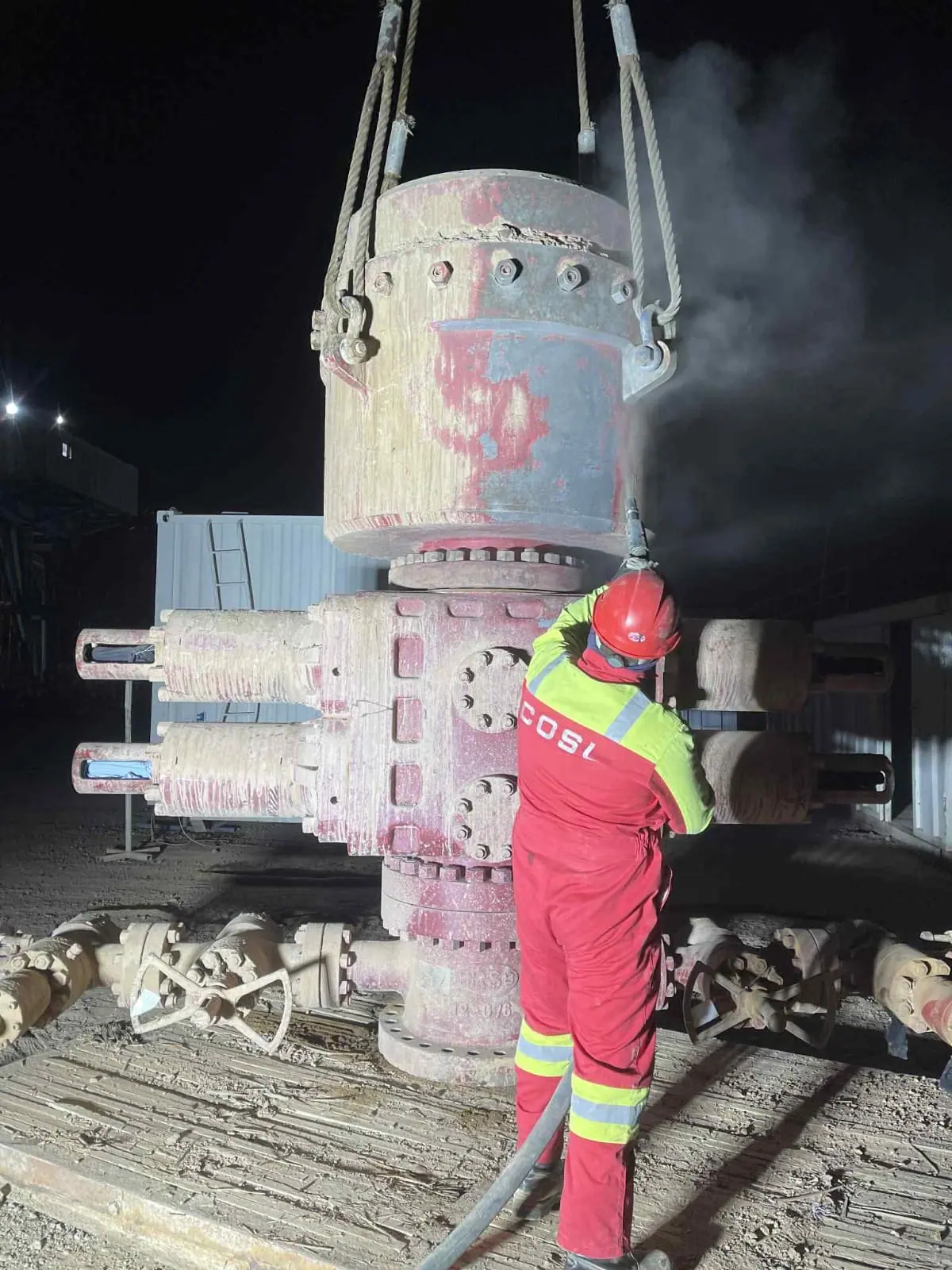Crew member beside wellhead equipment