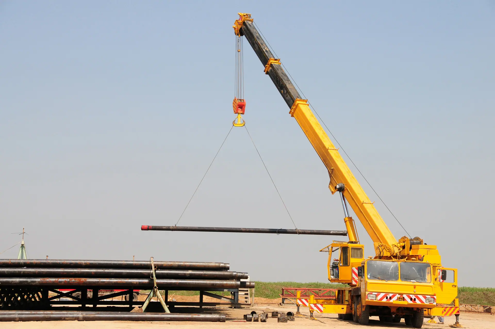Crane lifting pipe at a yard